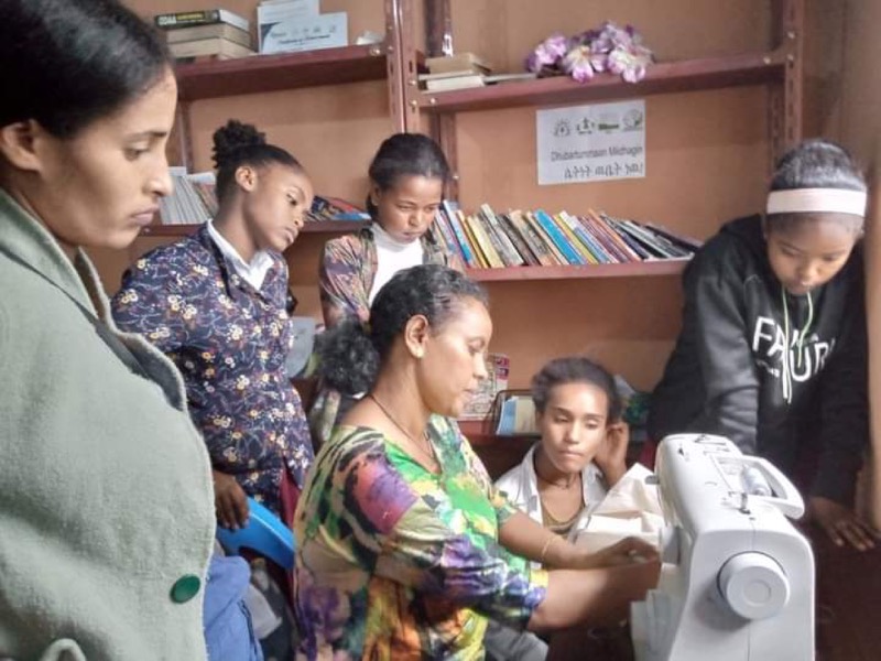 Des jeunes femmes autour d'une machine à coudre pendant une formation.