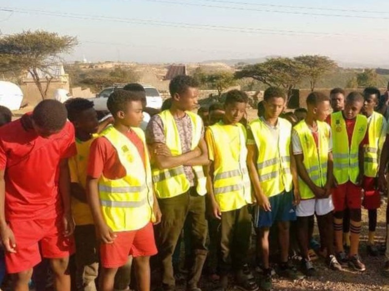 Un groupe de jeunes en gilets de sécurité jaunes, prêts pour une action communautaire en plein air.